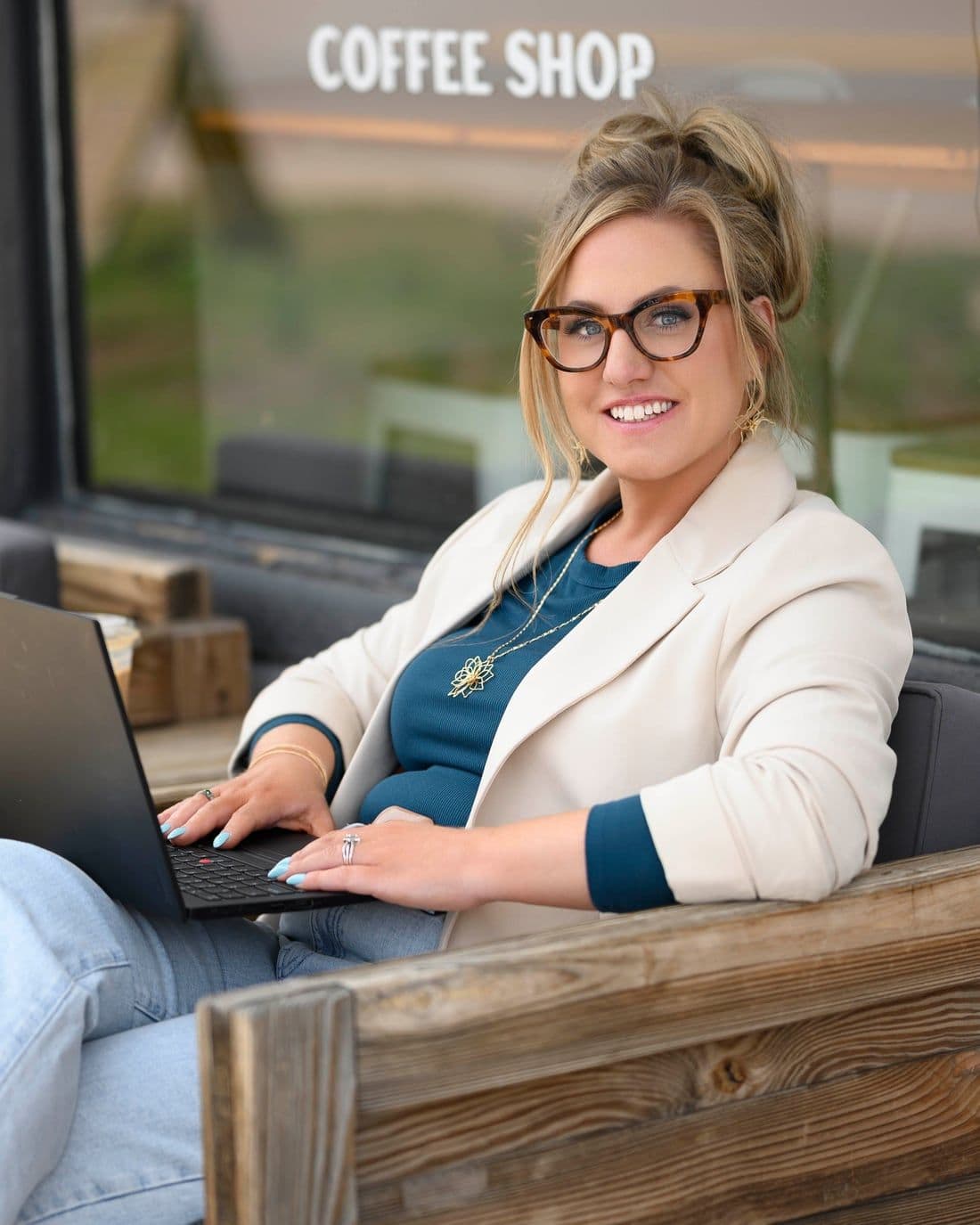 Jen, social media strategist for small business, smiling warmly at a coffee shop