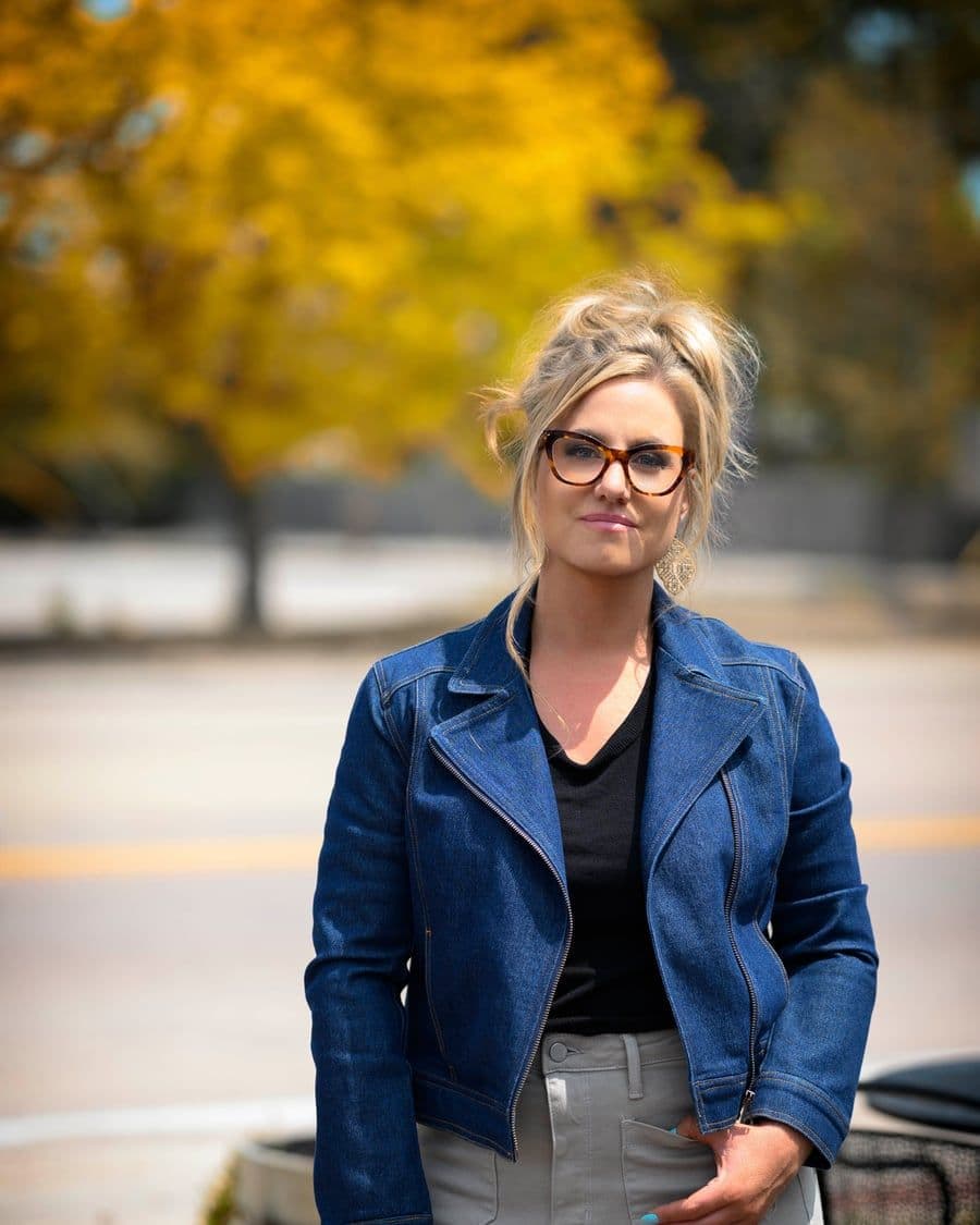 Jen outdoors in a denim jacket on a warm autumn day, calm and direct, ready to talk honestly about what an ad budget can do